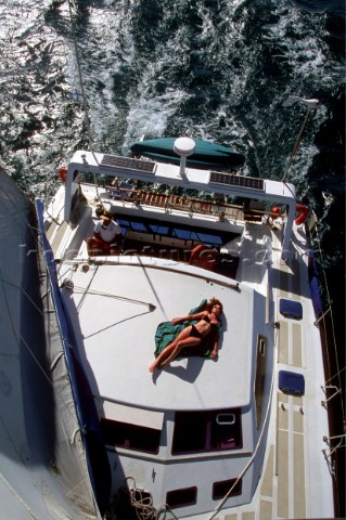 Woman sunbathing on deck of yacht  blue water crsuising