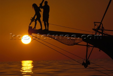 Romantic sunset as a couple stand on a classic yacht bow sprit in the Malvies Indian Ocean