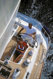 Aerial view of man helming a yacht behind relaxing female passenger
