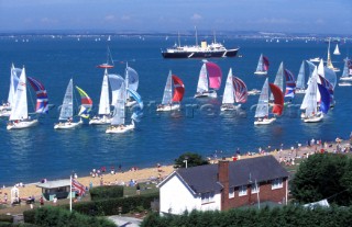 Fleet racing downwind off the coast of Cowes, Isle of Wight with the Royal yacht Britania in the background