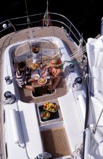 Couple Eating on Board - Aerial Lifestyle - Charter 99 Girl model cruising holiday. Couple eating meal on deck.