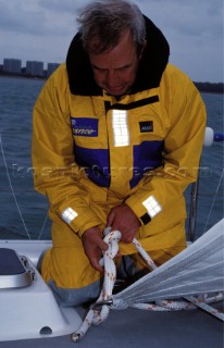 Man tying bowline knot in clew of sail