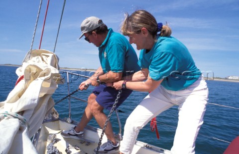 Two crew members pulling up the anchor 