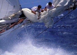 Two crew members changing sails on the bow of a classic yacht