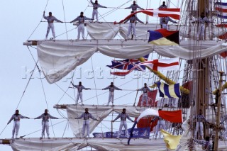 Crew of tall ship standing on footlines of yardarms as a ceremonial tradition