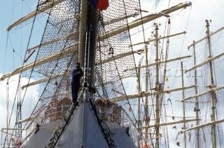 Crew member painting bow sprit on tall ship