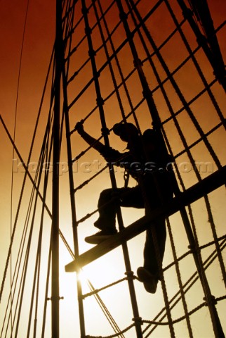 Silhouette of crew member climbing rigging on the tall ship Vespucci
