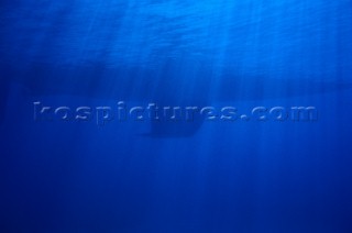 Keel of sailing yacht and rays of sunlight underwater