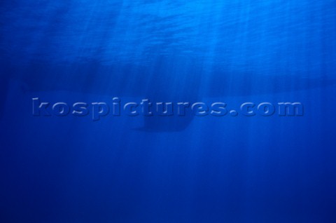 Keel of sailing yacht and rays of sunlight underwater 