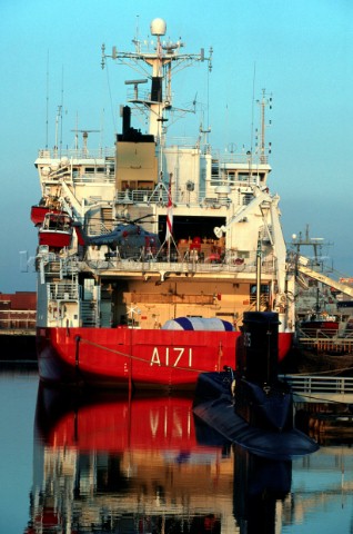 A submarine moored behind a merchant navy vessel