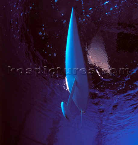Model yachts racing in a blue swimming pool shot from underwater with lighting showing keels and rud