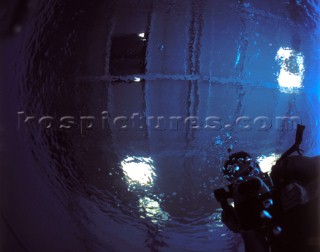 Silhouette of cameraman diver in a blue swimming pool shot from underwater with lighting