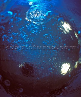 Rising air bubbles from scuba diver in a blue swimming pool shot from underwater with lighting