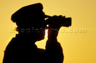 Silhouette of old Captain looking through binoculars