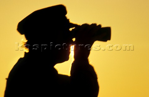 Silhouette of old Captain looking through binoculars