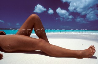 Tanned legs lying on sandy beach
