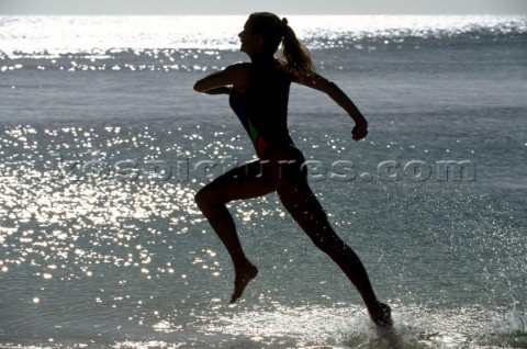 Silhouette of woman running through water along beach