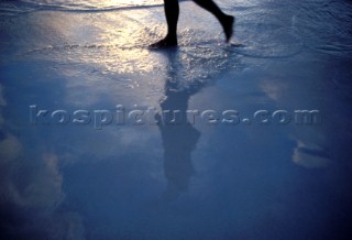 Reflections of the feet of a girl on wet sand jogging on the beach