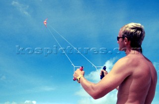 Man wearing sun glasses flying kite in clear blue sky