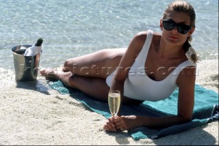 Woman lying on beach with glass of champagne