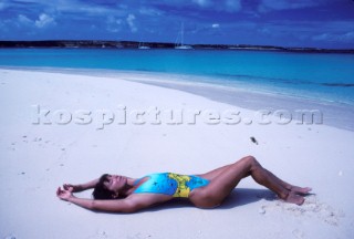 Woman lying on her back on sandy beach