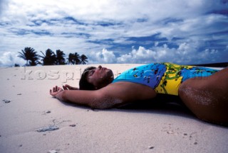 Close up of woman lying on her back on sandy beach