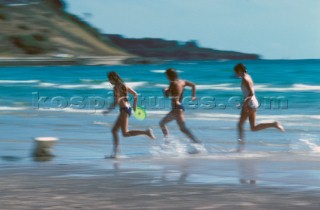 Three girls running along beach