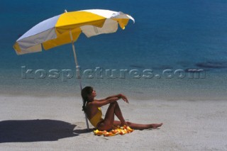 Woman relaxing under beach umbrella