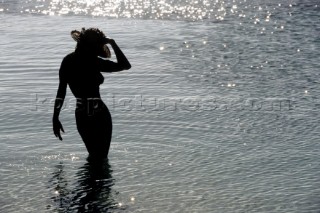 Silhouette of naked woman walking in sea