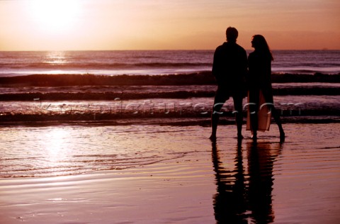 A couple take a romantic walk on a secluded beach at sunset