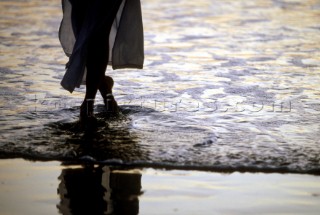 Silhouette of womans feet reflected in wet sand