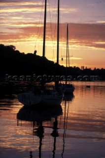 Two yachts moored on calm river at sunset