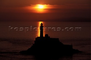 Fastnet rock and lighthouse at sunset on calm sea