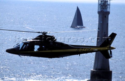 Helicopter flys passed Eddystone lighthouse whilst filming a racing yacht during the Fastnet Race