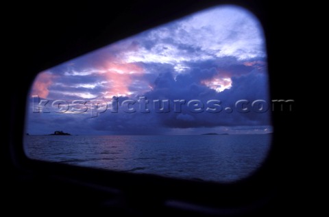 Sunrise in the Seychelles seen through the window onboard a yacht