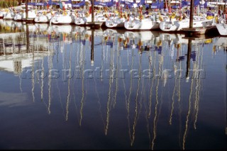 Yacht masts reflected in the still, flat water of marina