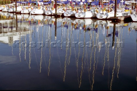 Yacht masts reflected in the still flat water of marina