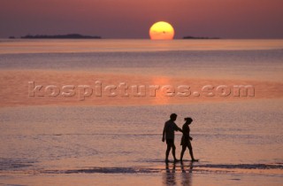A couple walking along the beach at sunset, Maldives