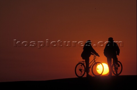 Two cyclists watch the sun go down