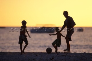 Family on beach playing football.