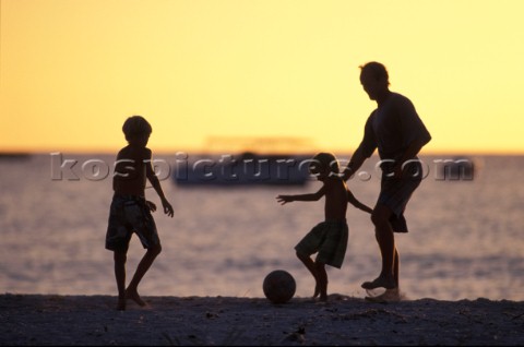 Family on beach playing football