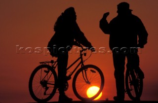 A couple on bicycles at sunset