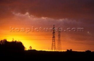 Two electricity pylons silhouetted against an incredible sunset