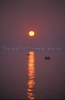 Two rowing boats on a calm sea at sunset