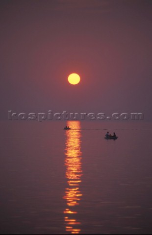 Two rowing boats on a calm sea at sunset