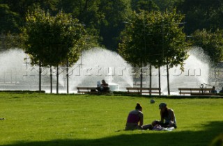 Two people relax by the fountains in Battersea Park, London