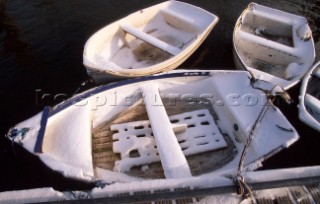 Four moored rowing dinghies covered in snow