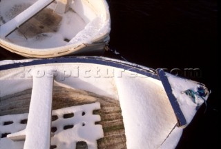 Two moored rowing dinghies covered in snow
