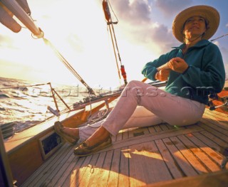 Girl helming classic sailing yacht Tenacity