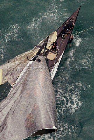 Crew member onboard Team New Zealands NZL82 try to cut away the jib and main sail after breaking the